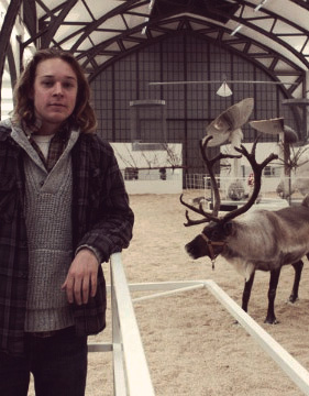 Sean visiting a reindeer at a farm.